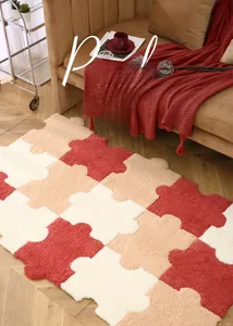 Detail of plush puzzle rug pieces in red and beige on a wooden floor