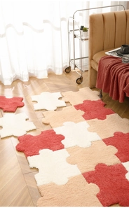 Detail of plush interlocking puzzle rug in white, apricot and brick red on wood floor