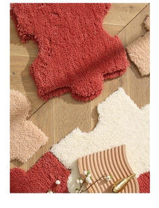 Detailed close-up of soft plush irregular shaggy rug with wavy edges on wooden floor
