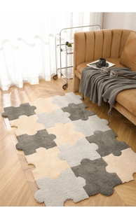 Detail of plush puzzle-shaped carpet with soft grey and beige interlocking foam rug pieces