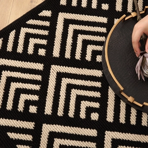 Washable checkered doormat with thick woven texture on light wood floor background