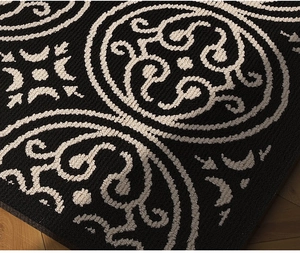 Detail of woven black kitchen mat with vintage white patterns and textured looped fibers