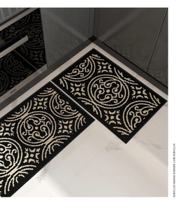 Detail of kitchen mat set with golden floral pattern on black woven anti-slip fabric