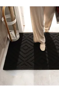 Close-up of black indoor doormat featuring geometric diamond pattern and durable texture