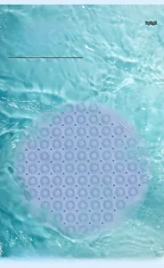 Detail of round light blue non-slip bath mat with massage texture over water surface