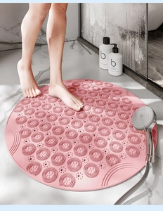 Pink round silicone shower mat with non-slip massage bristles on marble bathroom floor