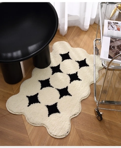 Detail of cream plush rug with black star patterns and wavy scalloped edges