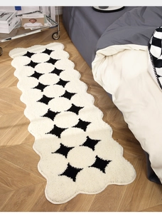 Close-up of soft plush bedside rug with black and white floral pattern and wavy edges