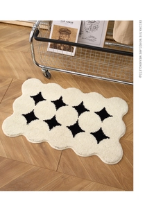 Close-up of irregular wavy cream rug with black star patterns on a wooden floor