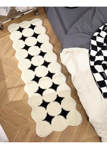 Macro detail of cream plush bedside rug with black star patterns and wavy edges