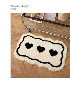 Detail of soft cream plush rug with wavy black borders and three black heart patterns