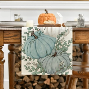 Detail of autumn table runner with pumpkin and eucalyptus leaves on a textured linen fabric