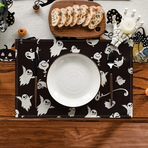 Close-up of Halloween placemat with white ghosts, ceramic plate and wooden cutlery on wood