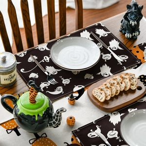 Detail of Halloween place mat with white ghost prints and woven texture on a dark table