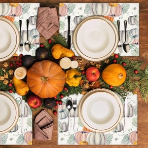 Close-up of elegant watercolor pumpkin placemats on a rustic wooden table setting