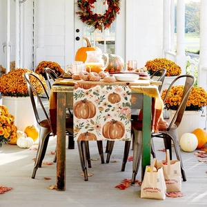 Detail of autumn table runner with watercolor pumpkin pattern on natural linen fabric