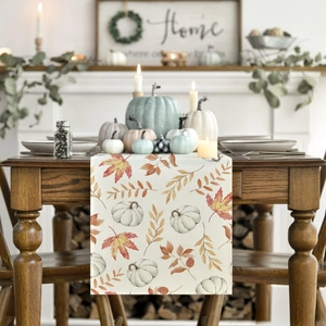 Detail of autumn table runner featuring hand-painted pumpkin and maple leaf patterns