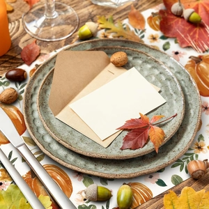 Close-up of fall harvest table runner with pumpkin patterns and nested ceramic plates