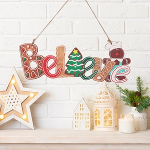 Close-up of a wooden 'Believe' ornament with gingerbread and Christmas tree motifs