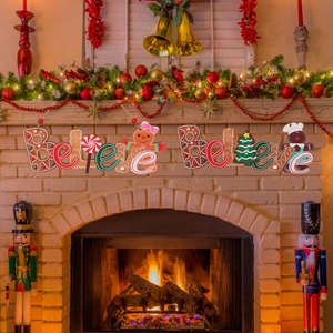 Christmas gingerbread man 'Believe' wooden banner hanging above a warm fireplace mantel