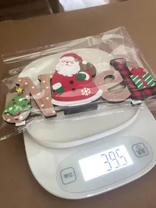 Detailed view of Noel wooden Christmas ornament being weighed on a digital scale