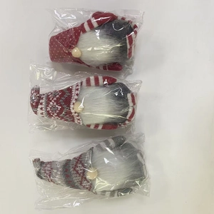 Détail de trois gnomes de Noël tricotés en rouge et gris avec des bonnets à motifs