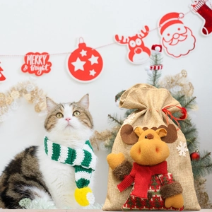 Close-up of burlap Christmas gift bag with plush reindeer and pet scarf set in festive scene