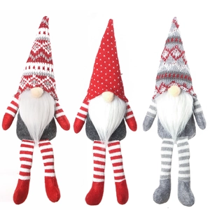 Trois gnomes de Noël avec de longues jambes et des chapeaux en tricot pour décoration