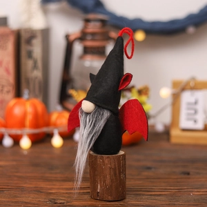 Gnomo di peluche per Halloween con cappello nero e ali di pipistrello rosse su legno