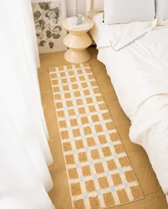 Detail einer flauschigen Schachbrett-Bettvorlage in Creme und Braun für das Schlafzimmer
