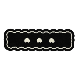 Black runner rug with white hearts and scalloped edges for bedroom or bedside use