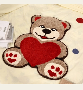 Détail du tapis peluche en forme d'ours avec un cœur rouge pour chambre d'enfant