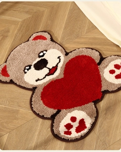 Gros plan d'un tapis doux en forme d'ours brun avec un cœur rouge sur parquet