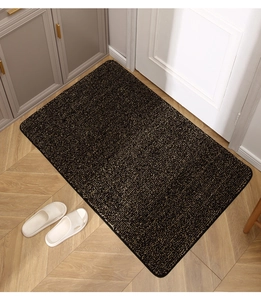 Primer plano del felpudo de entrada negro y dorado con textura de fibra y borde grueso