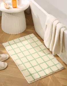 Close-up of cream and green checkered bathroom mat with soft plush texture on wood floor