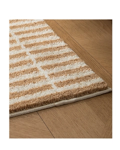 Close-up of thick striped plush rug fibers showing high-density tufted texture and soft pile