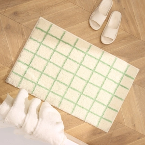 Green checkered bathroom rug made of soft microfiber on a warm wooden floor