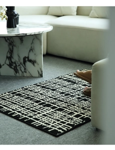 Detail of modern black and white geometric rug under a marble table in a living room