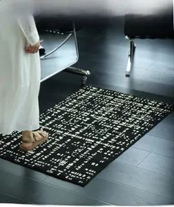 Detail of black and white geometric rug showing tufted texture on dark wood floor
