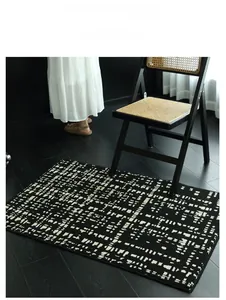 Detail of faux wool rug with black and white geometric patterns on dark wood flooring