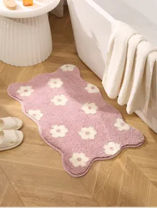 Close-up of soft pink bath mat with white floral pattern on a light wooden floor