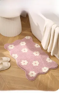 Close-up of pink flower bath mat with plush microfiber texture on a wooden floor