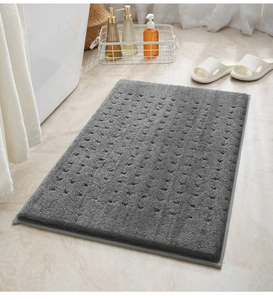Dettaglio del tappetino da bagno in peluche grigio scuro con trama antiscivolo tonda