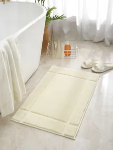 Detailed view of the thick fluffy texture and geometric pattern of the cream bath mat