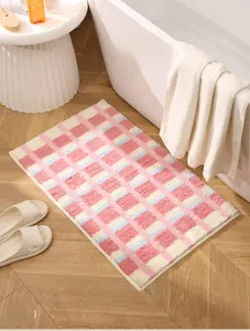 Détail d'un tapis de bain moelleux à carreaux rose et bleu sur un sol en bois chaleureux