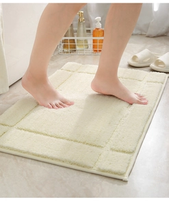 Plush cream bathroom mat showing soft texture and geometric relief on tile floor