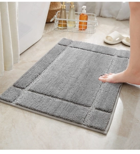 Thick grey absorbent bath mat with geometric border design on a marble bathroom floor