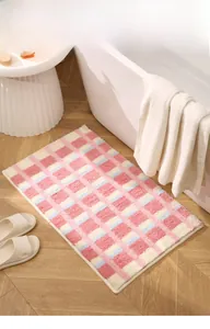 Détail de la texture pelucheuse du tapis de bain absorbant à carreaux rose et bleu