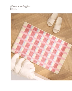 Gros plan d'un tapis de bain à carreaux pastels sur parquet avec texture moelleuse