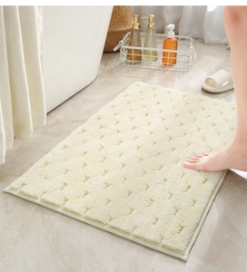 Detail van dikke crèmekleurige badmat met antisliptextuur en hoog absorptievermogen